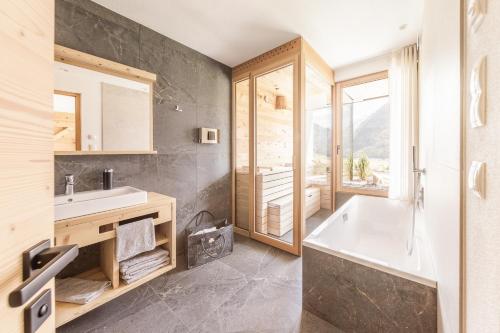 a bathroom with a tub and a sink and a window at Innermoser Bauernhof - Chalets in Molini di Tures