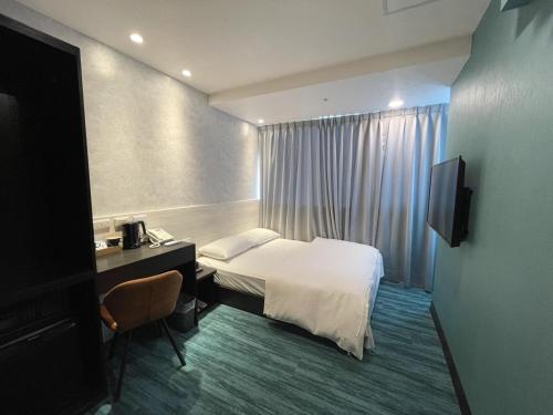 台北市にある西門雲町旅店 Sky Gate Hotelのベッド、デスク、テレビが備わるホテルルームです。