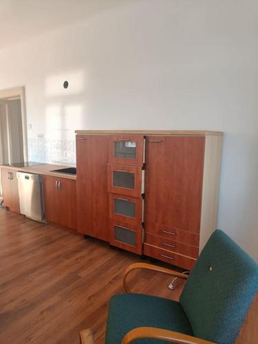 una cucina con armadi in legno e una sedia verde di Apartmán Procyon a Prostějov