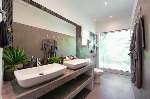 a bathroom with two sinks and a large mirror at ORCHID LODGE SAMUI - Bed & Breakfast in Lamai