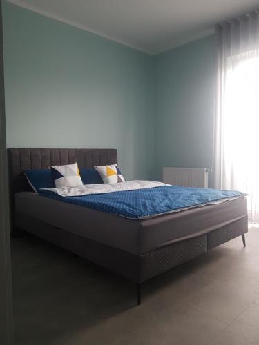 a bedroom with a bed with blue sheets and pillows at Apartament ul. Marzeń in Kostrzyn nad Odrą