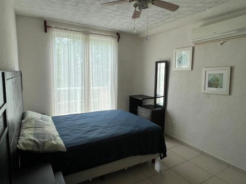 ein Schlafzimmer mit einem blauen Bett und einem Fenster in der Unterkunft Acapulco Marina Diamante in Acapulco