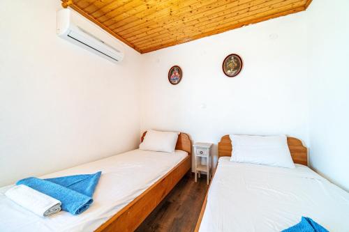 two beds in a room with white walls and wooden floors at Captain Spiros House in Lákones