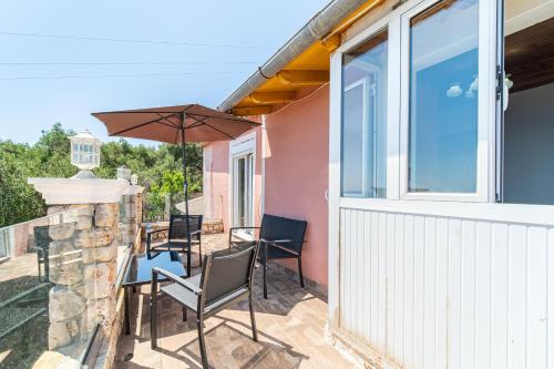 a patio with a table and chairs and an umbrella at Captain Spiros House in Lákones