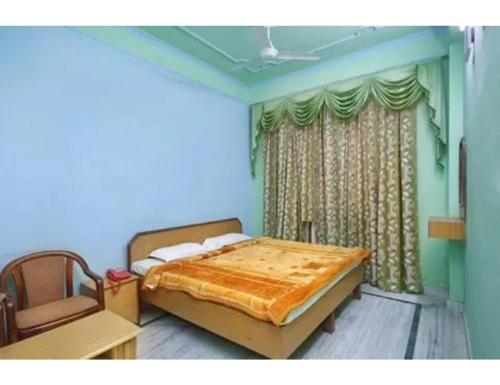 a bedroom with a bed and a chair and a window at Viren Plaza, Agra in Agra