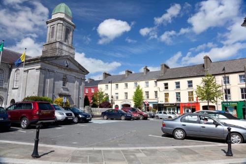 un estacionamiento con autos estacionados frente a un edificio en The Coachmans Inn en Roscommon