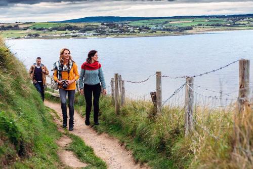 two women walking down a path next to a body of water at Tour House, A Country Escape set in Natures Beauty in Youghal