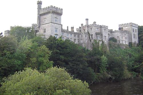 a castle sitting on top of a hill next to a river at Tour House, A Country Escape set in Natures Beauty in Youghal