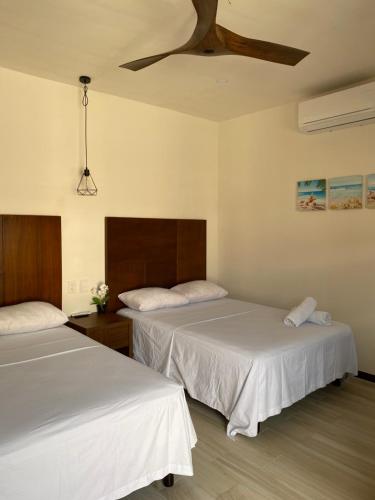 2 camas en una habitación con sábanas blancas en Hotel San Julio, en Celestún