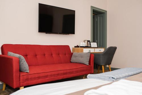 a living room with a red couch and a television at Conacul Törzburg in Bran