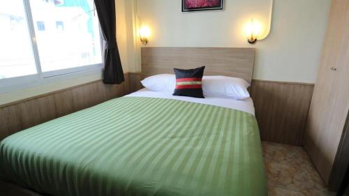um quarto com uma cama verde com uma almofada em Sukhumvit 20 Guest House em Bangkok