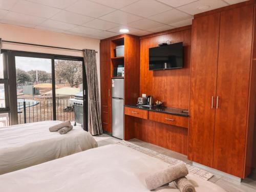 a hotel room with two beds and a television at Lethabong Lodge in Thabazimbi