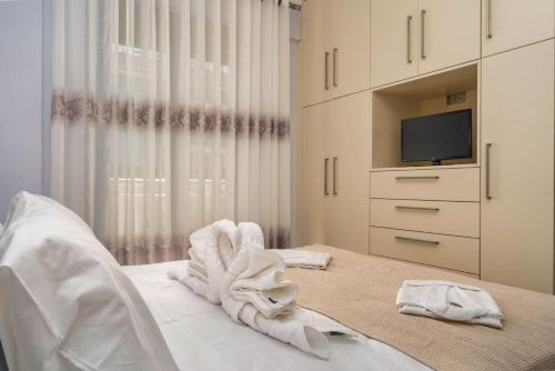 a bedroom with white towels on a bed with a tv at Villa Debora in Zakynthos Town