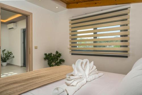 a bedroom with a white bed with a window at Villa Debora in Zakynthos Town