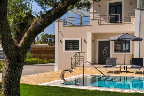 a house with a swimming pool and an umbrella at Villa Debora in Zakynthos Town