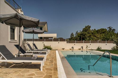 a swimming pool with two lounge chairs and an umbrella at Villa Debora in Zakynthos Town