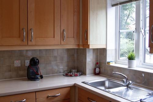 una cucina con armadi in legno, lavandino e finestra di Spacious 2 bedroom apartment in Central Oxford a Oxford