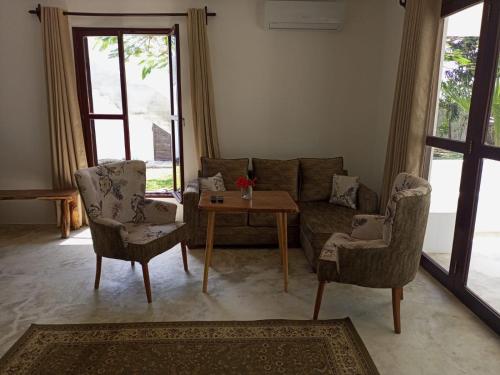 a living room with a couch and two chairs and a table at Sonrisa Villas in Diani Beach