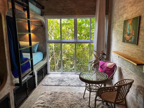 タオ島にあるWonderland Jungle Hostelのテーブルと椅子、窓が備わる客室です。