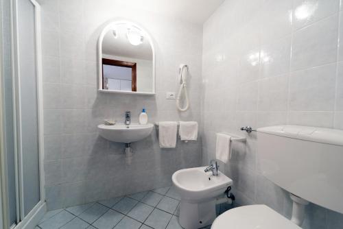 a white bathroom with a sink and a toilet at Gavila's Residenza Turistico Alberghiera in Porto Azzurro