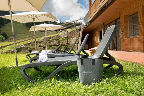 a chair with an umbrella and a trash can at Almhotel Hochhäderich in Riefensberg