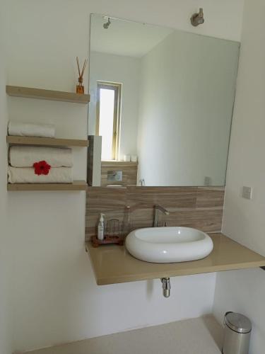 a bathroom with a sink and a mirror and towels at Sonrisa Villas in Diani Beach
