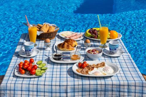 a table with plates of food and drinks next to a pool at Honeymoon Beach Studios in Perivolos