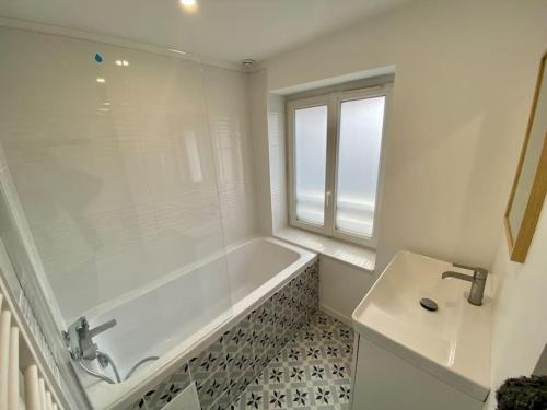 a white bathroom with a tub and a sink at L’Eucalyptus in Rouen