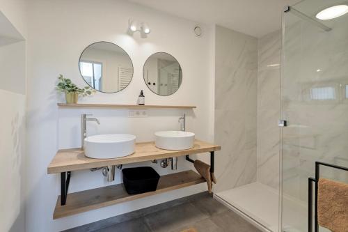 a bathroom with two sinks and a shower at Luxe strandappartement met zonneterras & parking in Koksijde