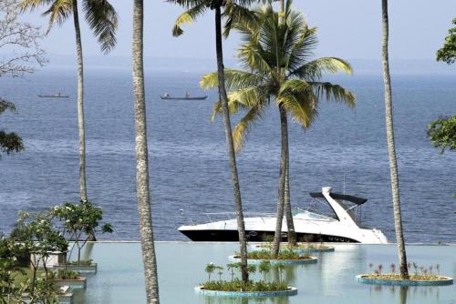 a boat in the water next to palm trees at Rhythm Kumarakom in Kumarakom