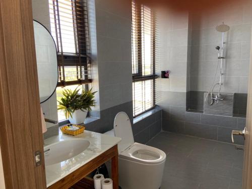 La salle de bains est pourvue de toilettes, d'un lavabo et d'une douche. dans l'établissement Biệt thự - Cafe Path Way, 