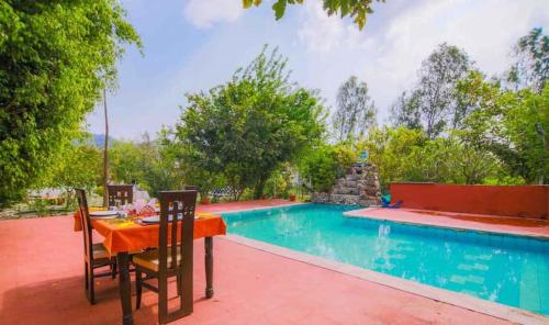 a table and chairs next to a swimming pool at Wildlife Resort Jim Corbett in Kālāgarh