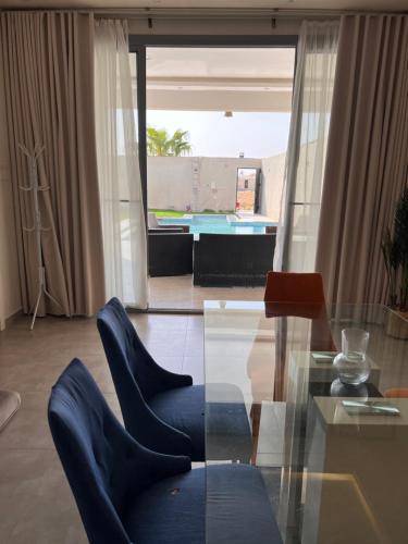 een woonkamer met een glazen tafel en blauwe stoelen bij شالية راقي بمسبح وجلسات خارجية in ‘Ilb