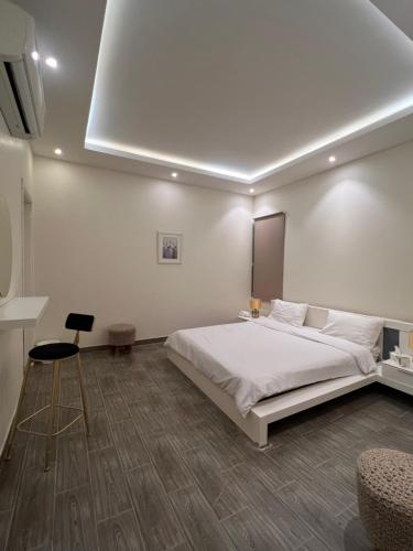 a white bedroom with a large bed and a chair at شالية راقي بمسبح وجلسات خارجية in ‘Ilb