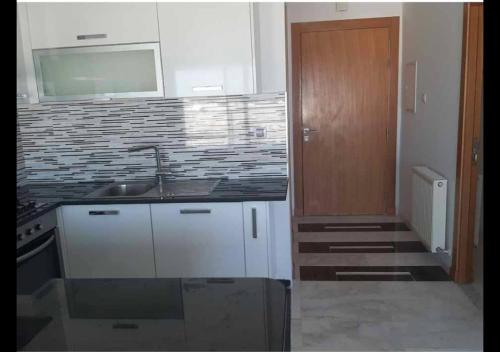 a kitchen with a sink and a wooden door at Panamera vue mer 180 degré in Sousse