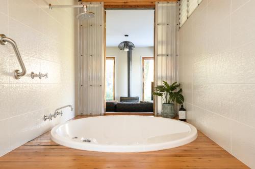 baño con una gran bañera blanca y ventana en Azidene House & Spa Apartment, en Daylesford