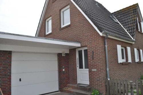a red brick house with a white garage at Nr 31 - Ferienhaus Am Yachthafen in Carolinensiel