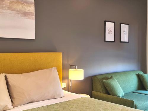 a bedroom with a bed and a green chair at Seaview Motel & Apartments in Apollo Bay