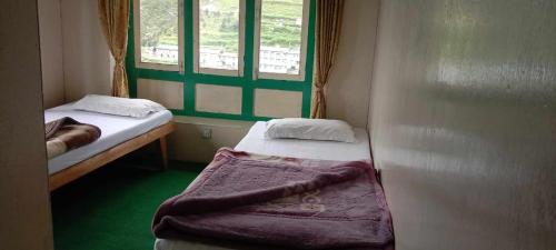 um pequeno quarto com 2 camas e uma janela em Hotel hillten em Namche