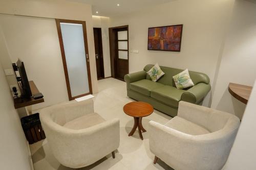 a living room with a couch and two chairs at Woodbine Foliage in Malappuram