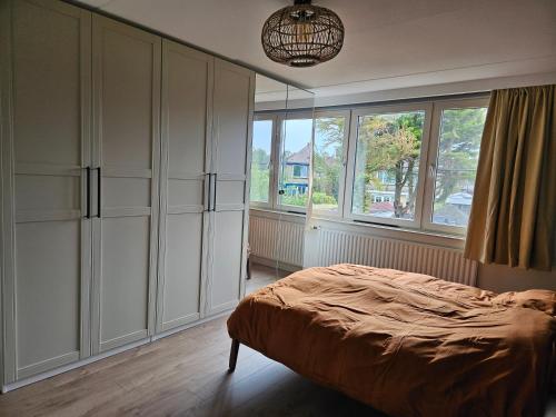 1 dormitorio con armarios blancos, 1 cama y ventana en Sabai Sabai Huis en Egmond aan den Hoef