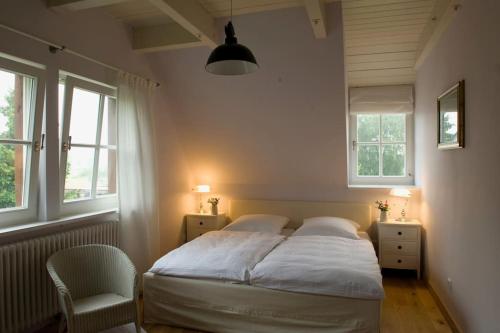 a bedroom with a bed and a chair and two windows at Ruhiges Landhaus Krienke - Doppelhaus mit Sauna & Kamin in Rankwitz