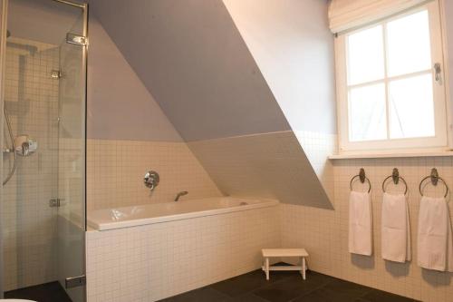 a attic bathroom with a bath tub and a window at Ruhiges Landhaus Krienke - Doppelhaus mit Sauna & Kamin in Rankwitz