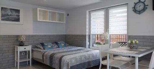 Schlafzimmer mit einem Bett, einem Tisch und einem Fenster in der Unterkunft Dom Wczasowy FALA in Darłówko