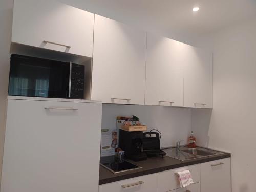 a kitchen with white cabinets and a black microwave at Superior Beach Aparthotel in Lido di Jesolo