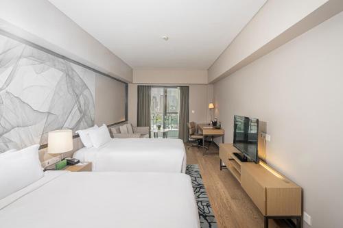 a hotel room with two beds and a flat screen tv at Riverdale Residence Xintiandi Shanghai in Shanghai