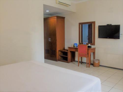 a bedroom with a bed and a desk and a television at Pia Hotel in Cirebon