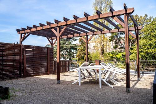 a wooden pergola with white tables and chairs under it at Hotel Rio Bidasoa in Hondarribia