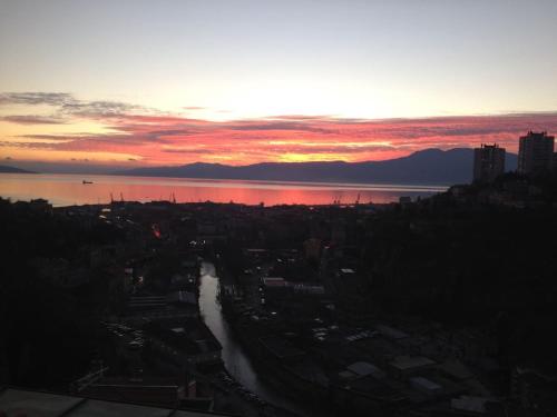 a view of a city with the sun setting over the water at Eagle's Nest in Rijeka
