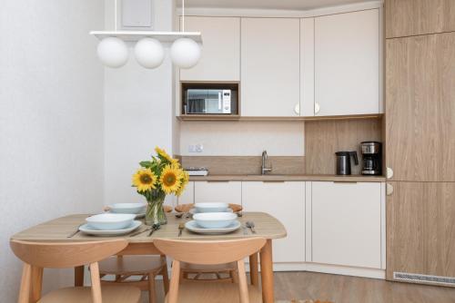 a kitchen with a wooden table with chairs and a vase of flowers at Sun & Beach Apartments Bel Mare with Parking by Noclegi Renters in Międzyzdroje